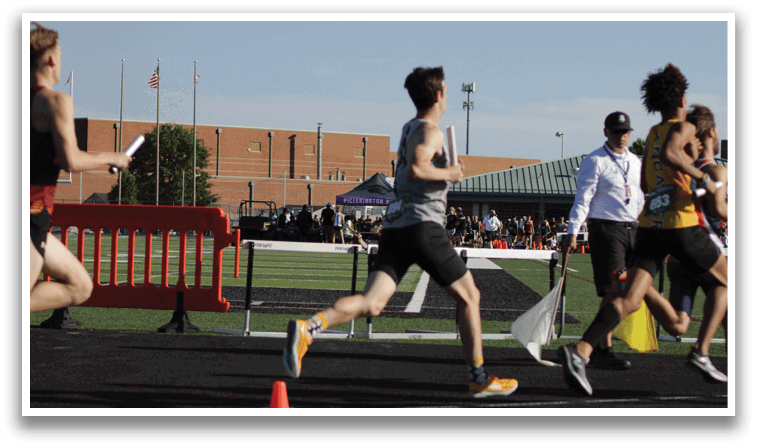 A man running on a track with a cone in front of him. Description generated by AI