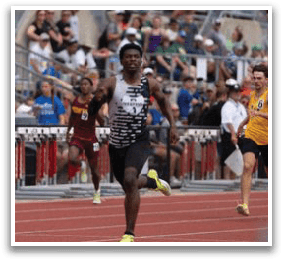 A man running on a track with a crowd watching. Description generated by AI