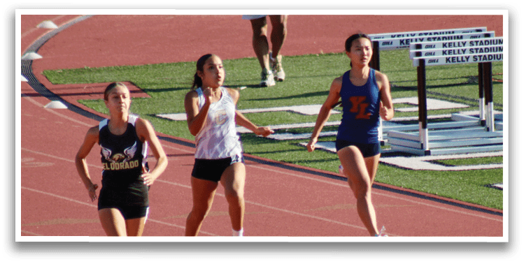 Three girls running on a track. Description generated by AI