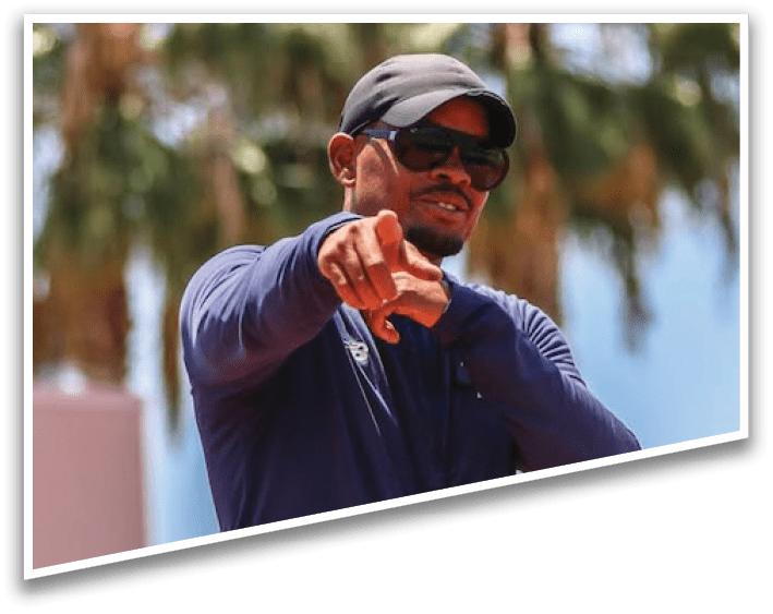 A man wearing a blue shirt and sunglasses pointing at something. Description generated by AI