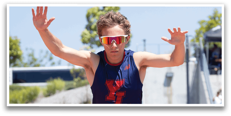 A man wearing a blue shirt and sunglasses is jumping in the air. Description generated by AI