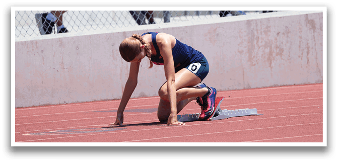 A woman is kneeling on a track. Description generated by AI