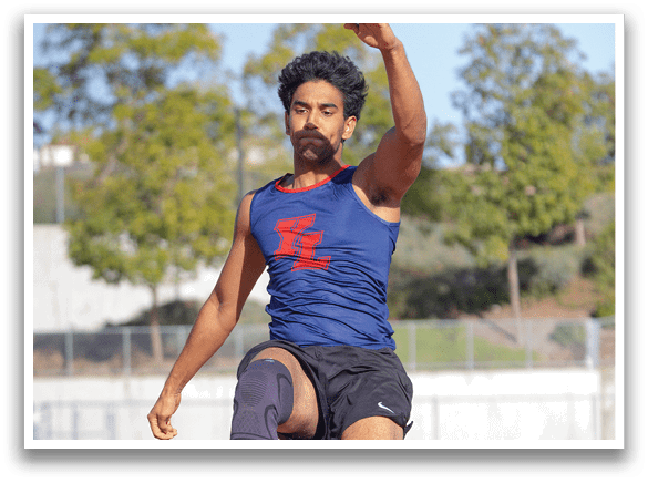 A man is jumping in the air on a track, wearing a blue shirt and black shorts. AI generated content