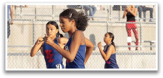 Three girls running on a track, one wearing a blue uniform. AI generated content