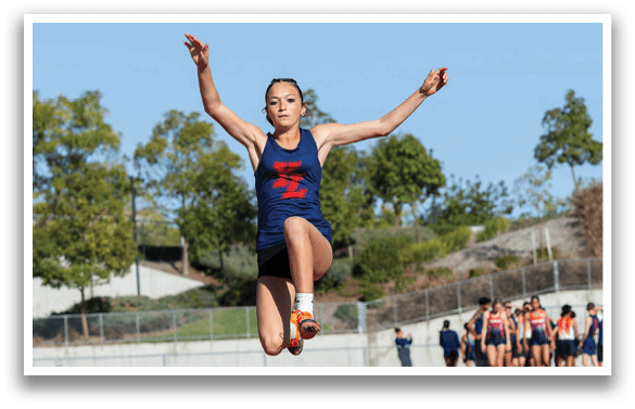 A woman is jumping in the air on a track, wearing a blue and red shirt. AI generated content