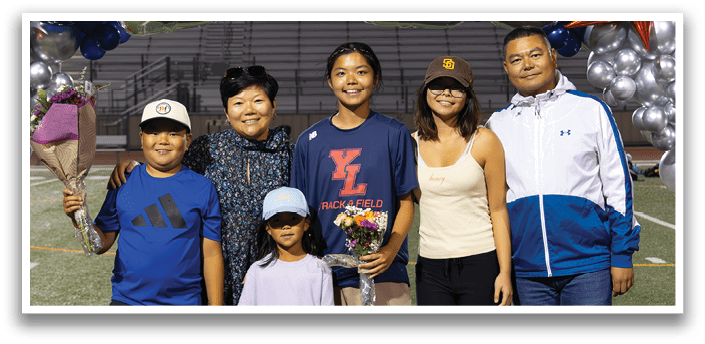 A group of people, including a woman and a man, pose for a picture in front of a banner that reads “2026." AI generated content