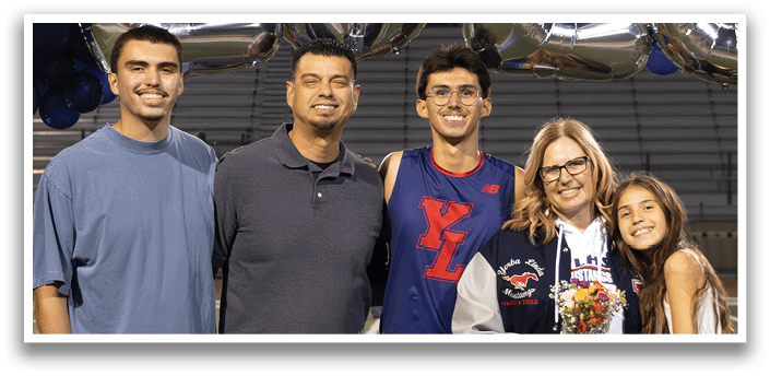 Four people pose for a picture on a football field. AI generated content