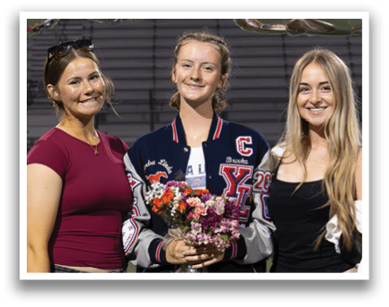 Three women pose for a photo on a football field. AI generated content