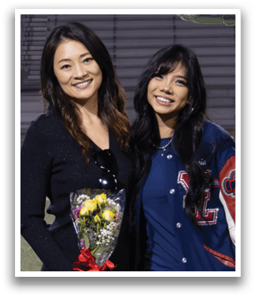 Two women pose for a picture in front of a banner that reads “2026." AI generated content