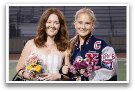 Two women standing on a football field, one holding flowers. AI generated content