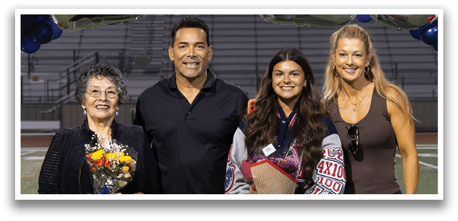 A group of four people, two men and two women, are standing on a football field in front of a banner that reads 2026. They are posing for a picture. AI generated content