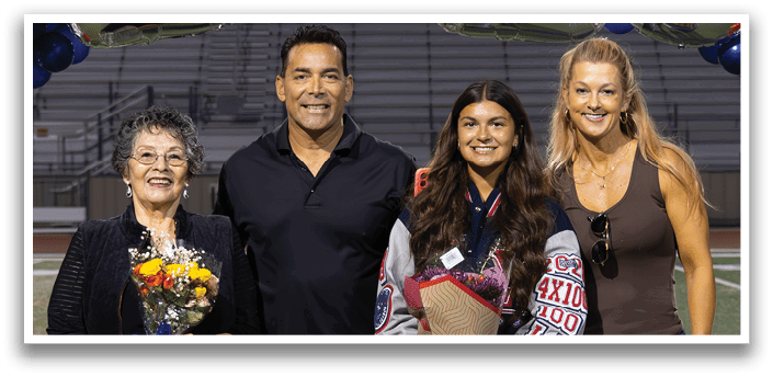 A group of four people, two men and two women, are standing on a football field in front of a banner that reads 2026. They are posing for a picture. AI generated content