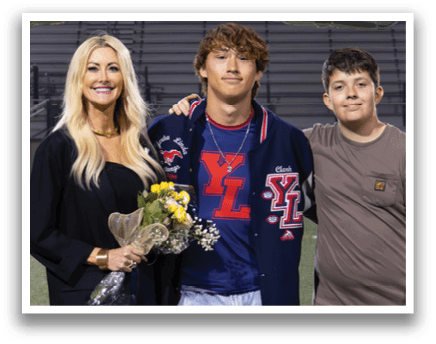 A man and woman stand on a football field, posing for a picture. The woman is holding a bouquet of flowers. AI generated content