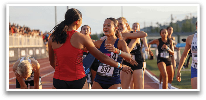 A group of women wearing number tags are hugging each other. Description generated by AI