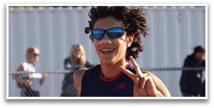 A man wearing a blue and red shirt is running on a track. Description generated by AI