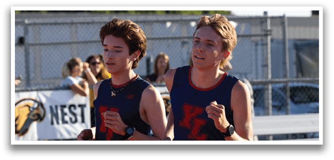 Two boys running on a track. Description generated by AI