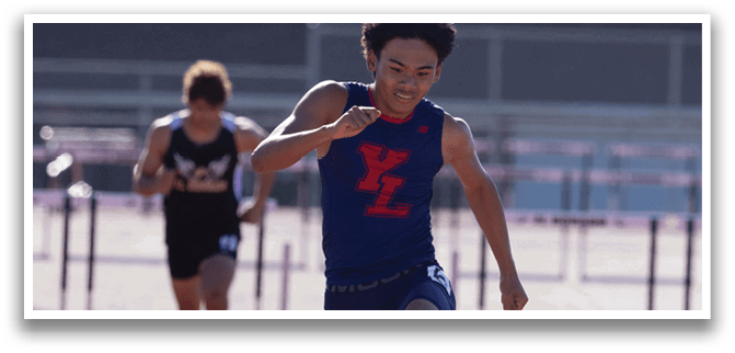 A man wearing a blue shirt and white socks is jumping over a hurdle. Description generated by AI