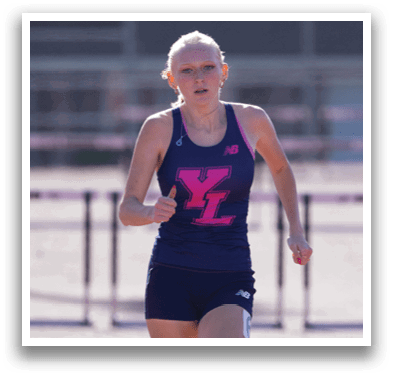 A woman running on a track with a pink and blue shirt. Description generated by AI