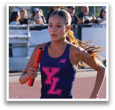 A woman running on a track with a pink and blue shirt. Description generated by AI