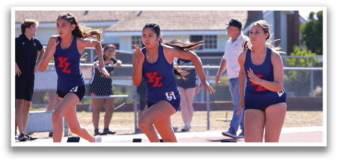 Three girls running on a track. Description generated by AI