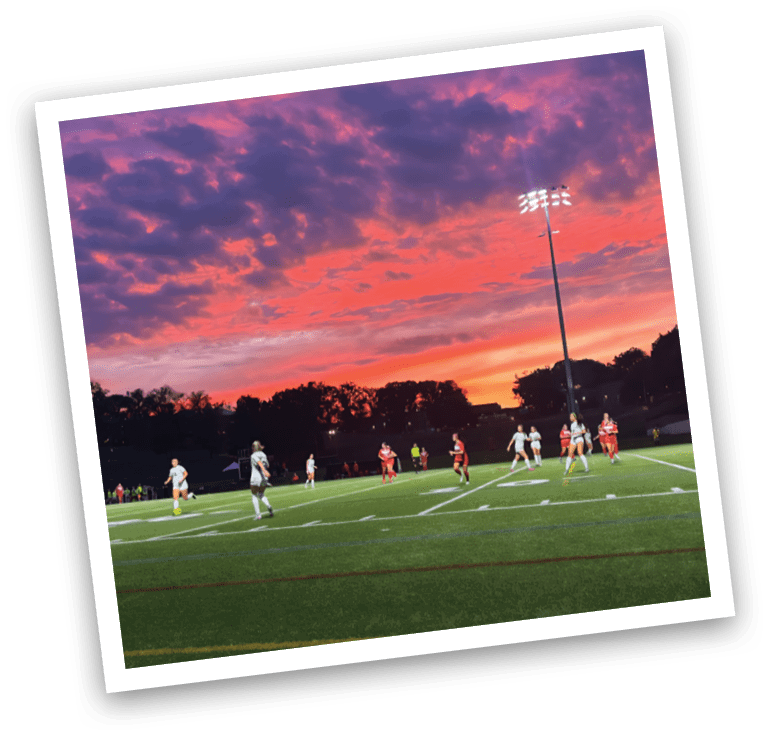 A group of people playing soccer on a field with a purple sky in the background. AI generated content