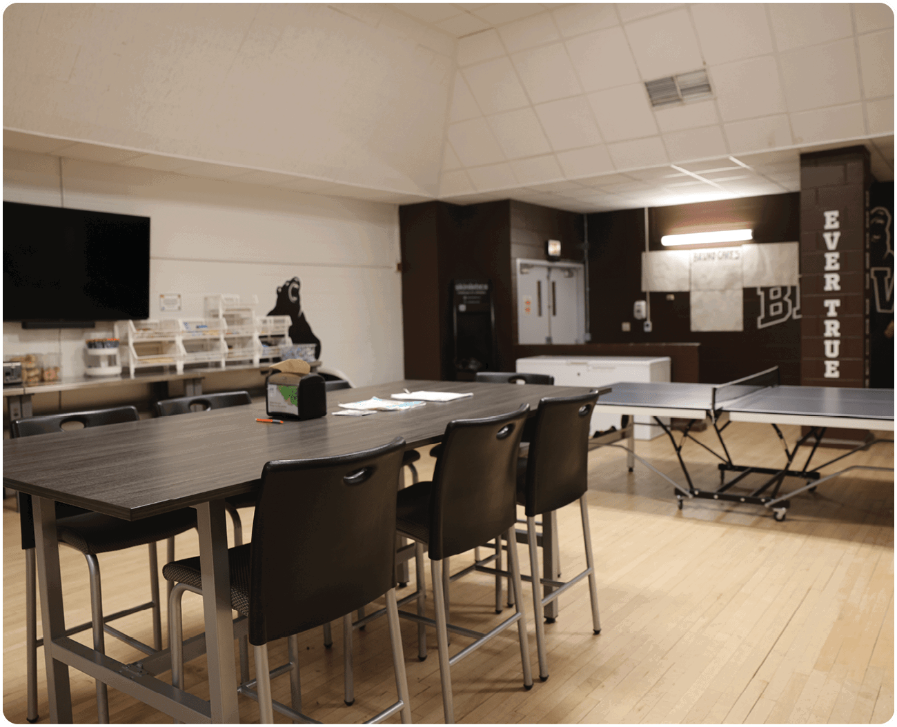 A room with a table and chairs, a TV, and a ping pong table. AI generated content