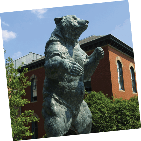A statue of a bear is standing on a pedestal in front of a building. AI generated content
