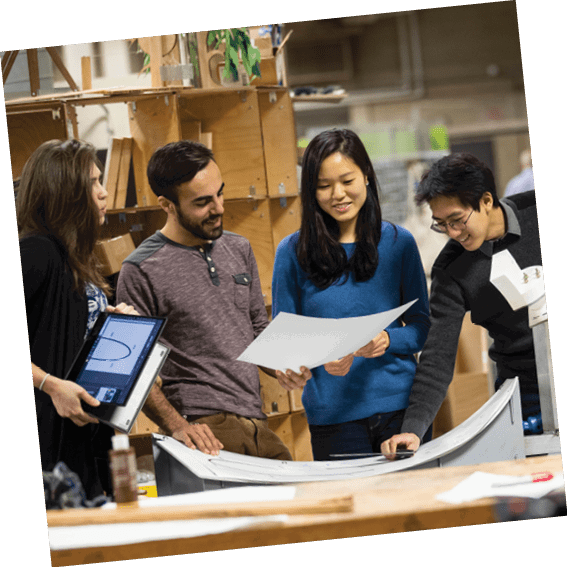 Four people are standing around a table with a large piece of paper on it. They are looking at the paper together, possibly discussing or working on a project. AI generated content