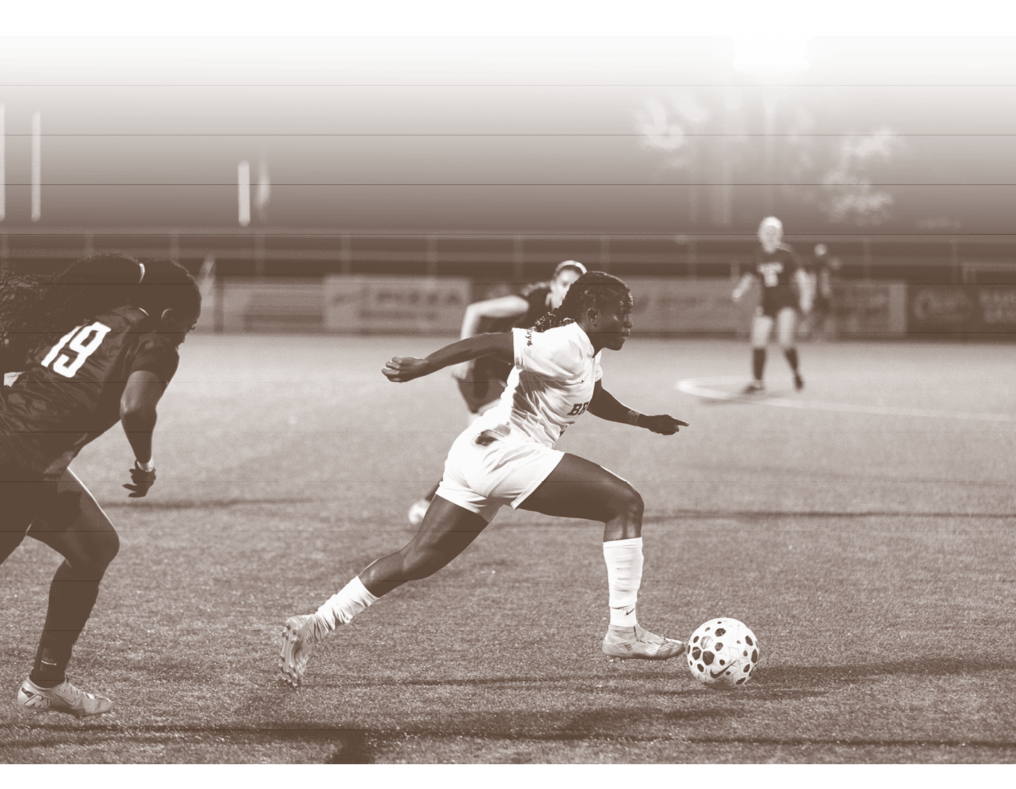 Two soccer players are running towards a soccer ball on a field. AI generated content