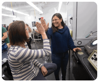 Two women are in a room, one sitting and the other standing. The standing woman is holding up her hand. AI generated content