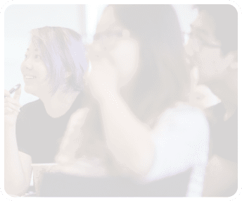 A woman with purple hair is applying makeup while sitting next to another woman. AI generated content