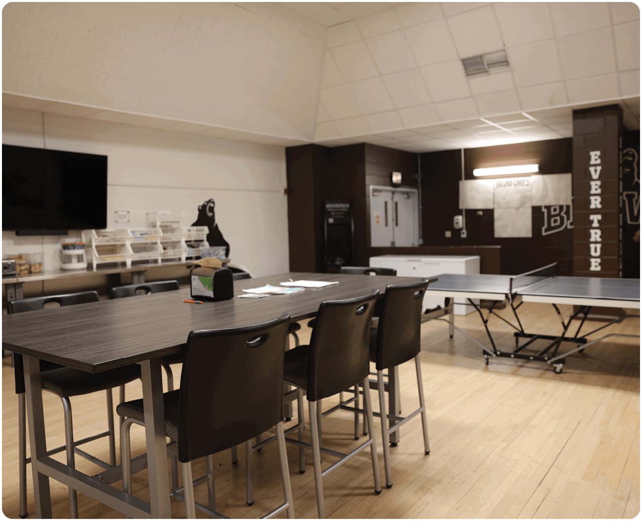 A room with a table and chairs, a TV, and a ping pong table. AI generated content