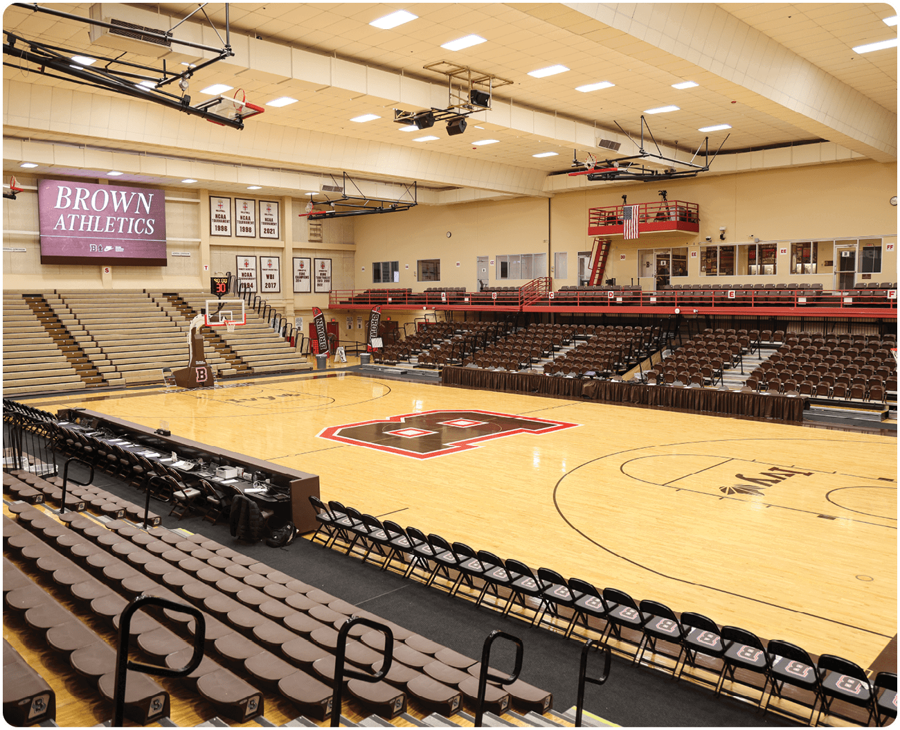 A basketball court with a scoreboard and a large audience seating area. AI generated content