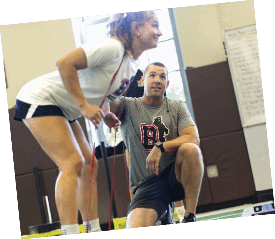 A man and woman are in a gym, the woman is standing on a bench and the man is sitting on a machine. AI generated content