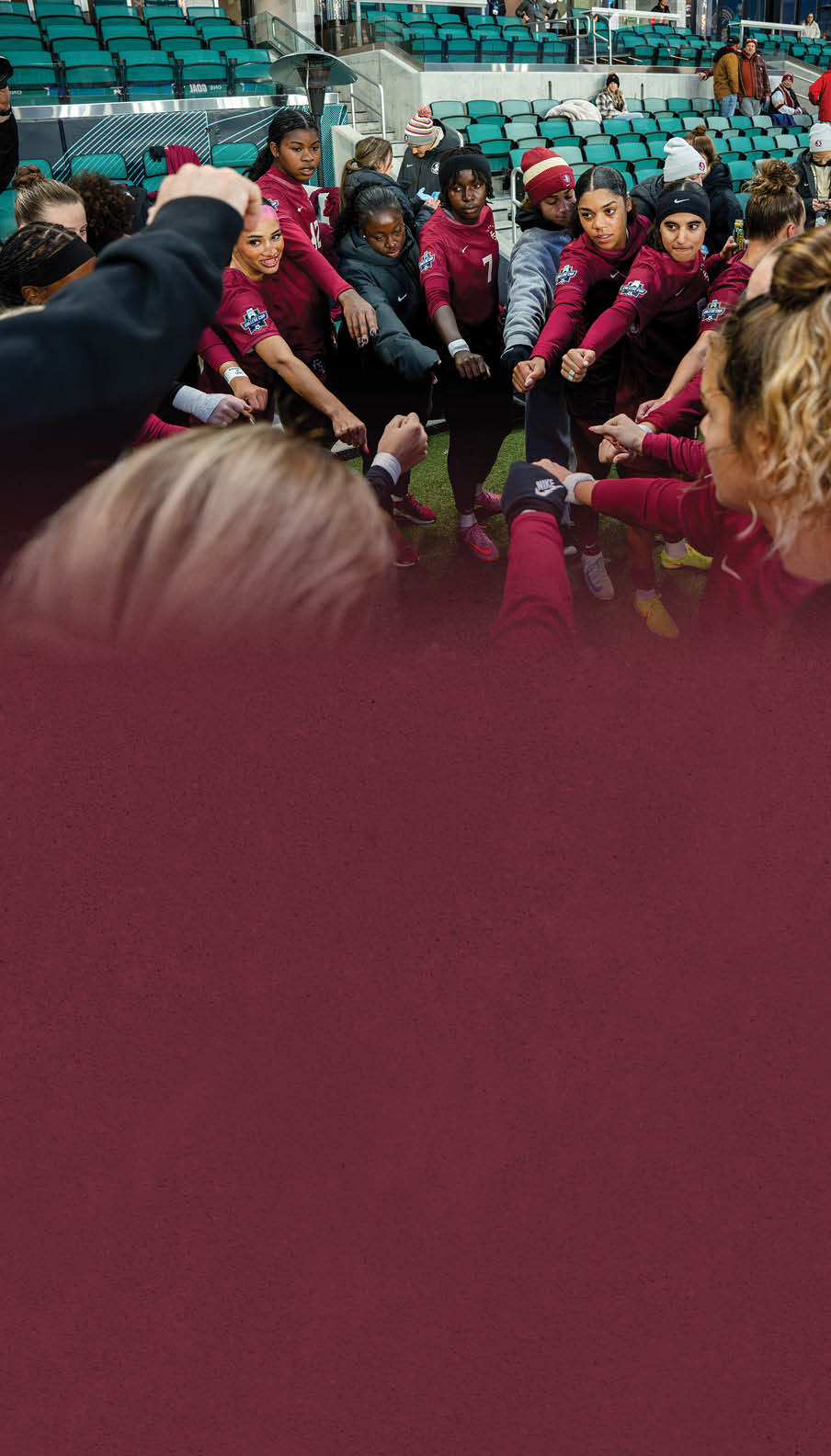 A group of women wearing red shirts and black shorts are huddled together on a field. AI generated content