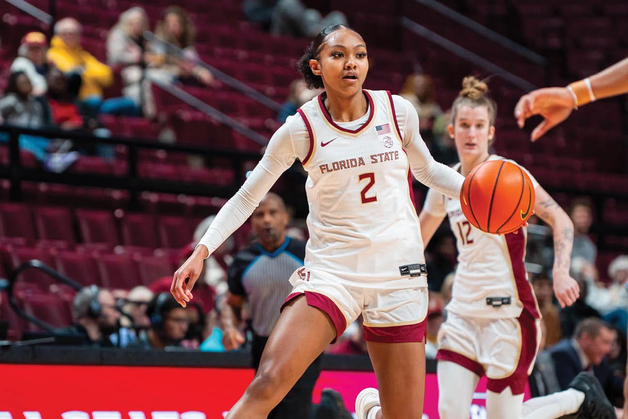Two female basketball players are running on the court, one holding a basketball. AI generated content