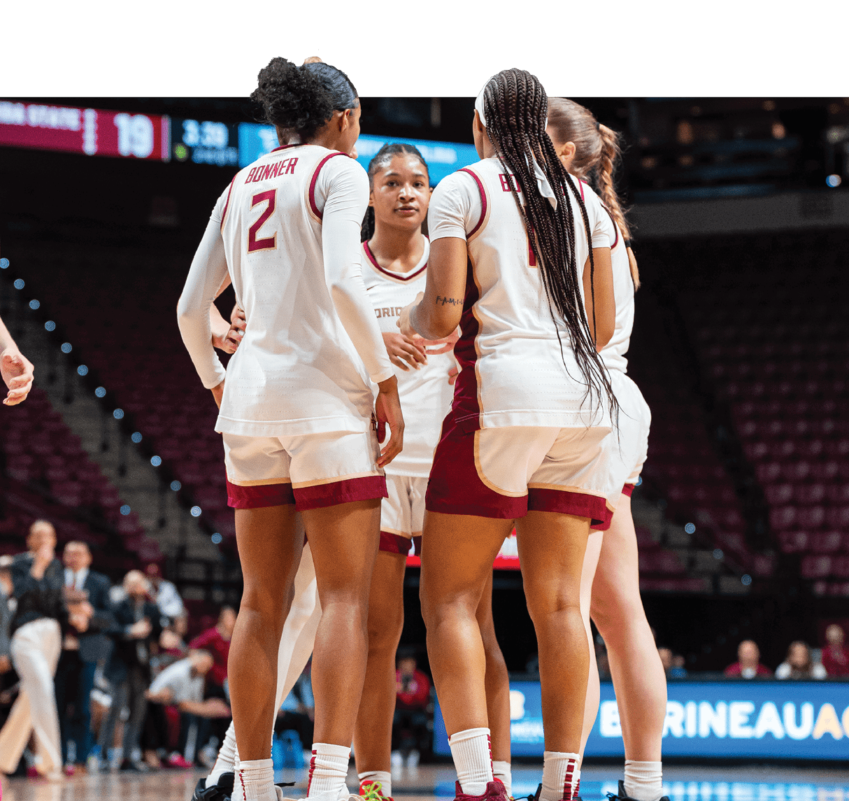 Three female basketball players wearing red and white uniforms are standing on the court, talking to each other. AI generated content