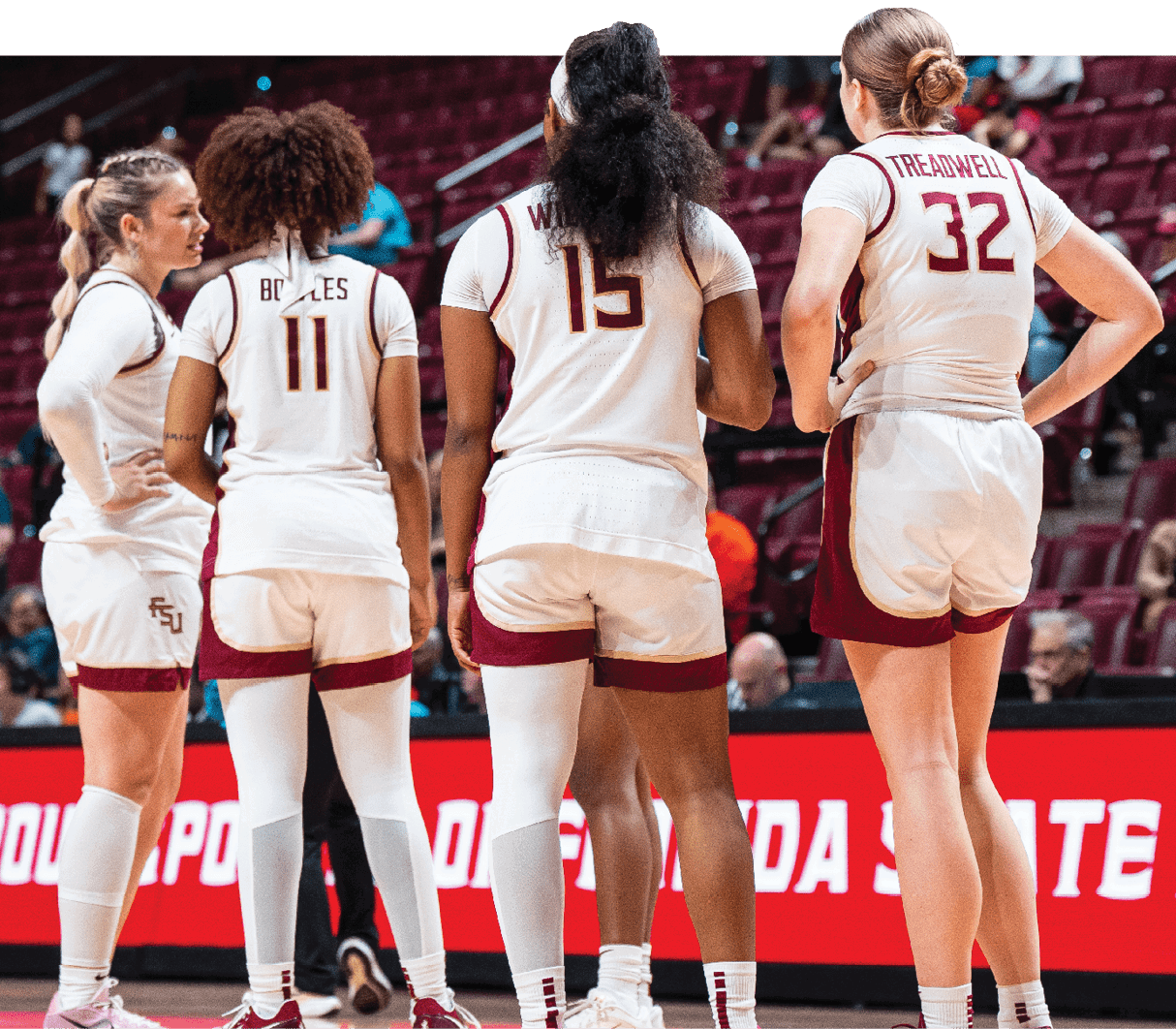 Four female athletes wearing white uniforms and red shoes stand on a basketball court. AI generated content