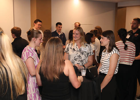 A group of people standing around a table with a black tablecloth. Description generated by AI