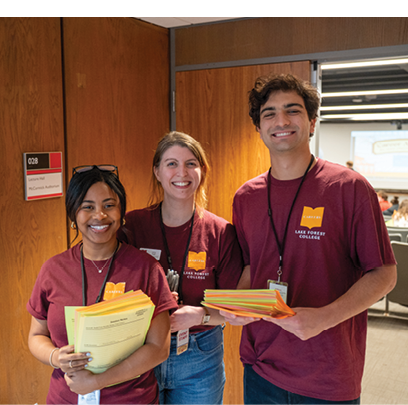 Three people wearing red shirts and holding papers. Description generated by AI