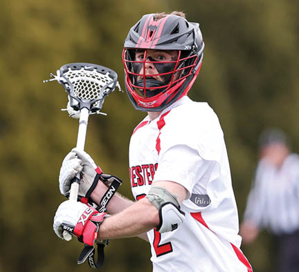 A man wearing a white and red shirt holding a lacrosse stick. Description generated by AI