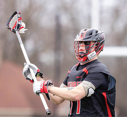 A man holding a lacrosse stick. Description generated by AI