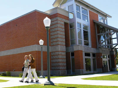 Two people walking on a sidewalk in front of a brick building. AI generated content
