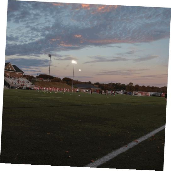 A group of people are standing on a soccer field at night. AI generated content