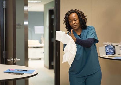 A woman in a blue shirt is standing in a room with a table and a mannequin. She is holding a piece of paper and appears to be looking at it. AI generated content