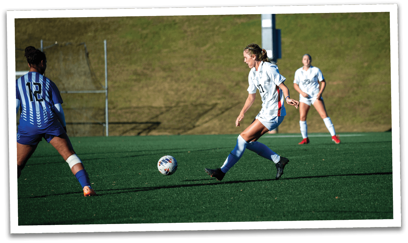 Three female soccer players are on the field, with one player in the center about to kick the ball. The other two players are positioned on the left and right sides of the field. AI generated content