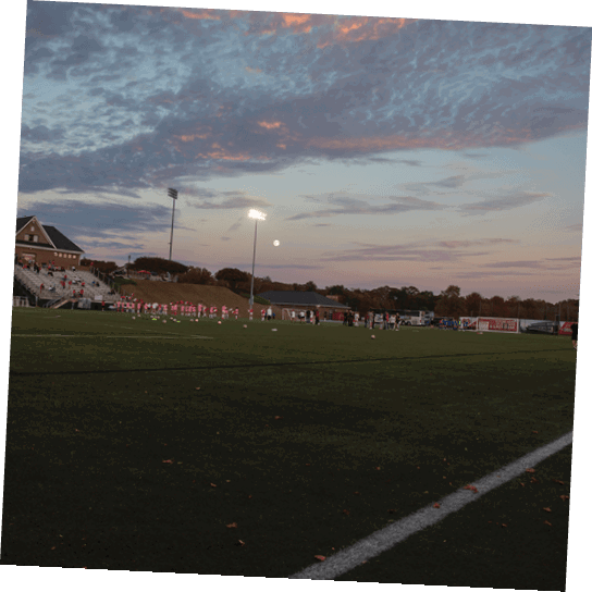 A group of people are standing on a soccer field at night. AI generated content
