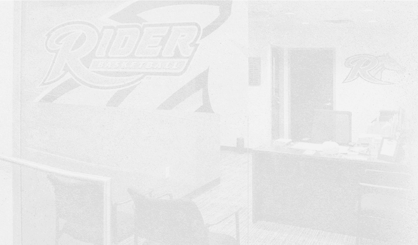 An office space with a desk, chairs, and a wall featuring a large “Rider Basketball" logo. Description generated by AI