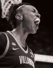 A person wearing a Villanova basketball jersey with the number 5 is celebrating on the court while another person in a UConn jersey is in the background. Description generated by AI