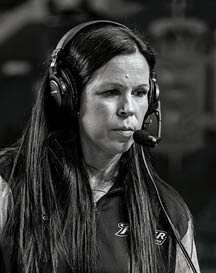 A person with long dark hair is wearing large black over-ear headphones against a blurred background. Description generated by AI